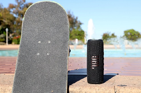 L'enceintee JBL Flip 6 est étanche et résistante aux chocs Enceinte jbl Flip 6 à cote d'un skate au bord d'une piscine