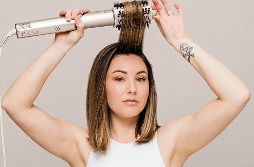 Le Shark FlexStyle et un seche-cheveux styler 5en1 Femme se coiffant avec un seche-cheveux styler